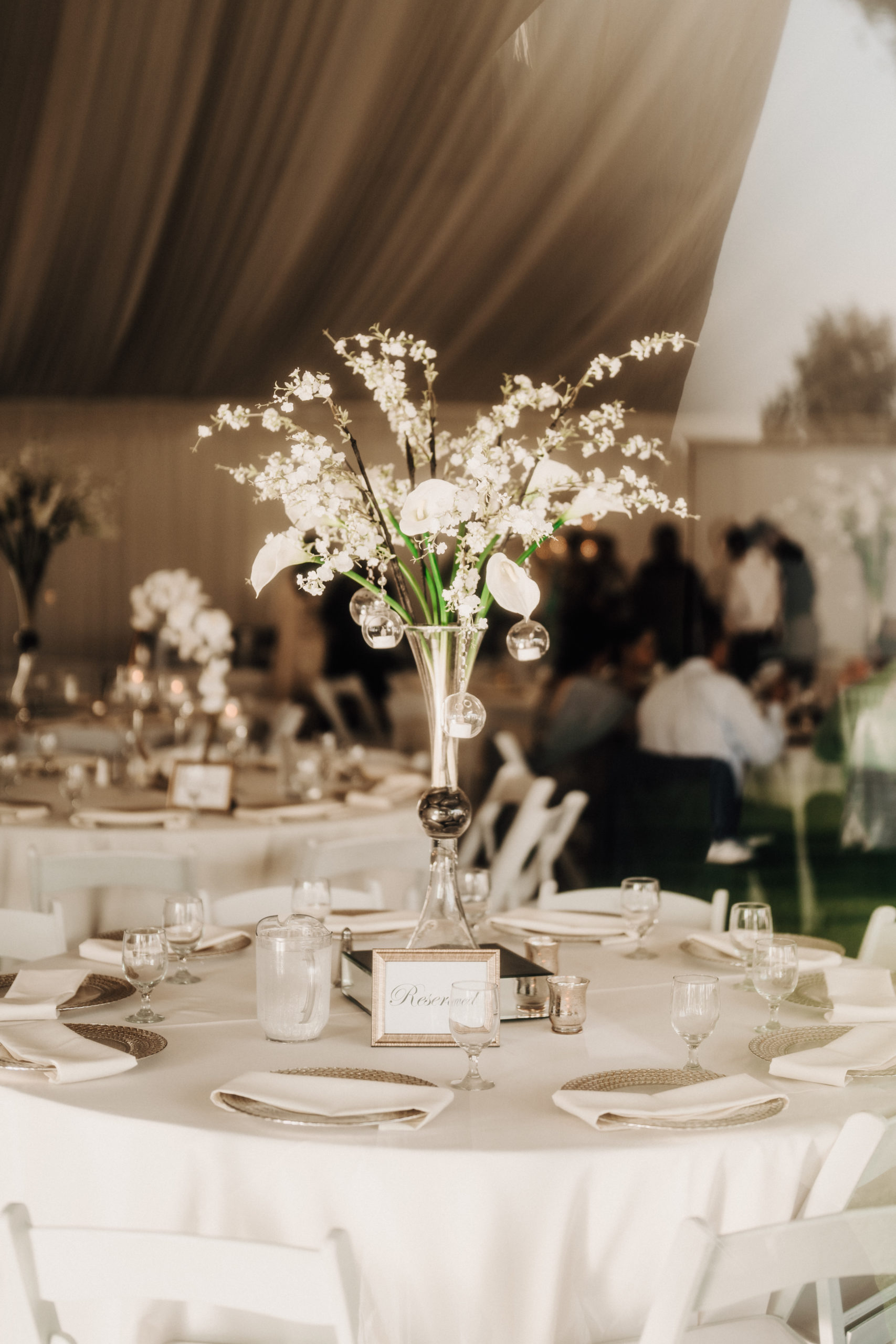 Wedding reception table with floral centerpiece, place settings, and glassware inside The Pavilion at Haggin Oaks, showcasing event décor and banquet seating for a Sacramento wedding.