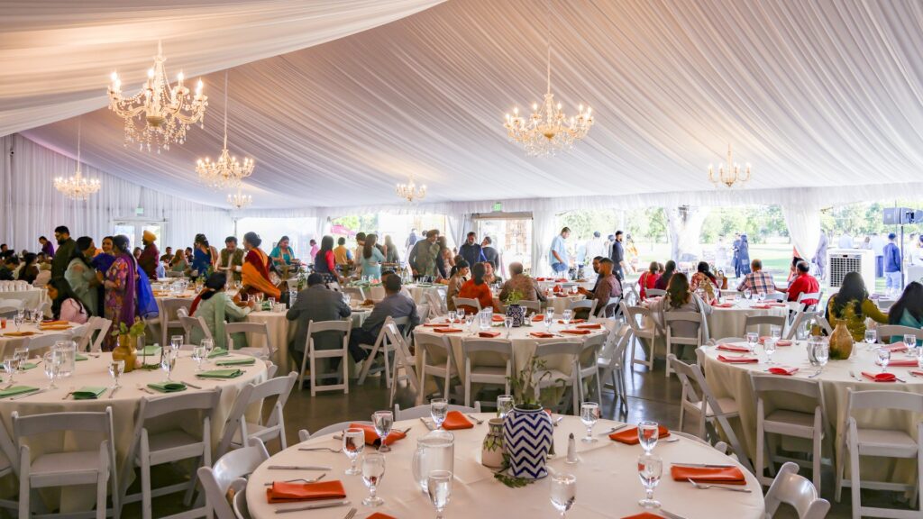 Reception guests seated beneath chandeliers inside The Pavilion at Haggin Oaks, showcasing banquet seating and event space for cultural celebrations, weddings, and private events in Sacramento.