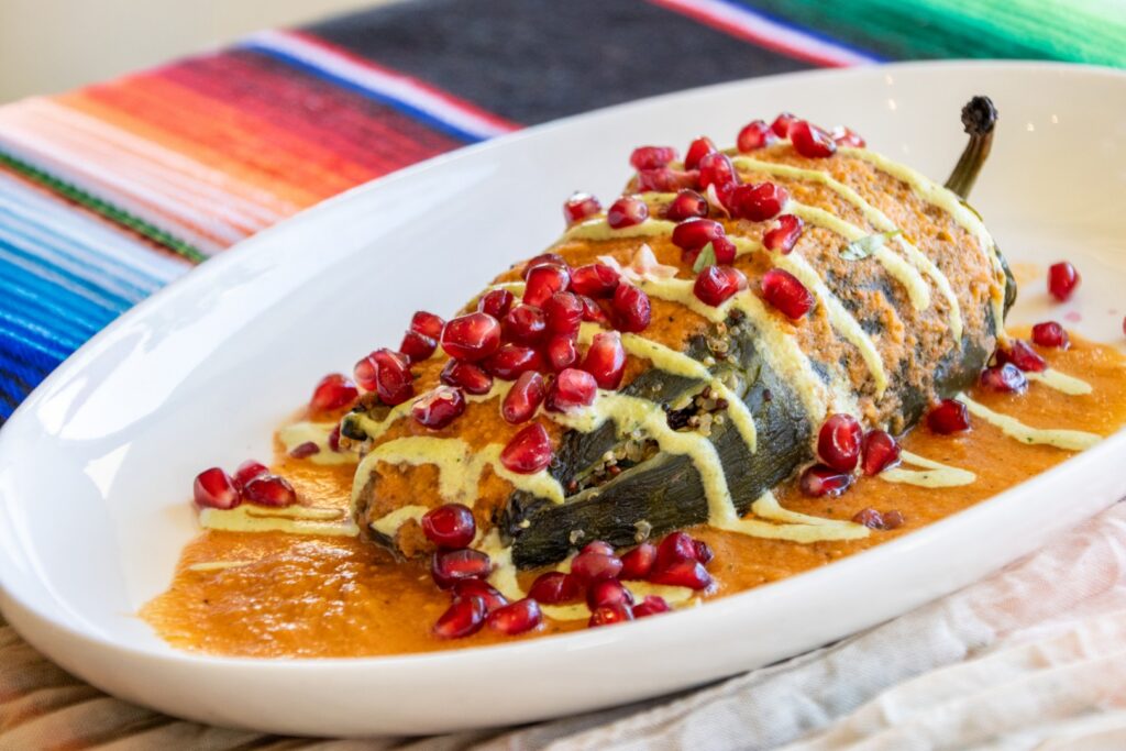 Chiles en nogada topped with pomegranate seeds and creamy walnut sauce, served as part of a Mexican-inspired catered event menu at The Pavilion at Haggin Oaks.