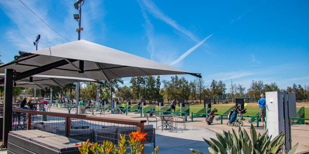 The Hangout at Haggin Oaks, a unique corporate event venue in Sacramento, features a spacious outdoor patio overlooking the Haggin Oaks driving range. Guests enjoy shaded seating, scenic golf course views, and a relaxed atmosphere