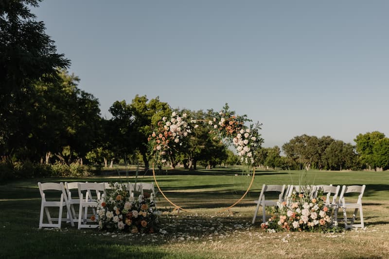 Outdoor wedding ceremony setup at Creekside at Haggin Oaks with a floral arch and golf course views.