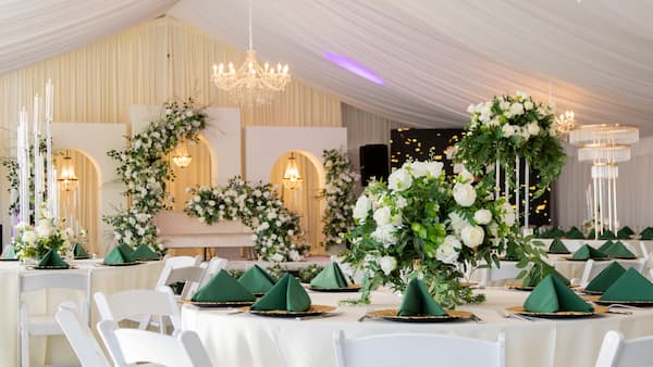 Indoor wedding reception at the Pavilion at Haggin Oaks with floral centerpieces, chandeliers, and decorated tables.