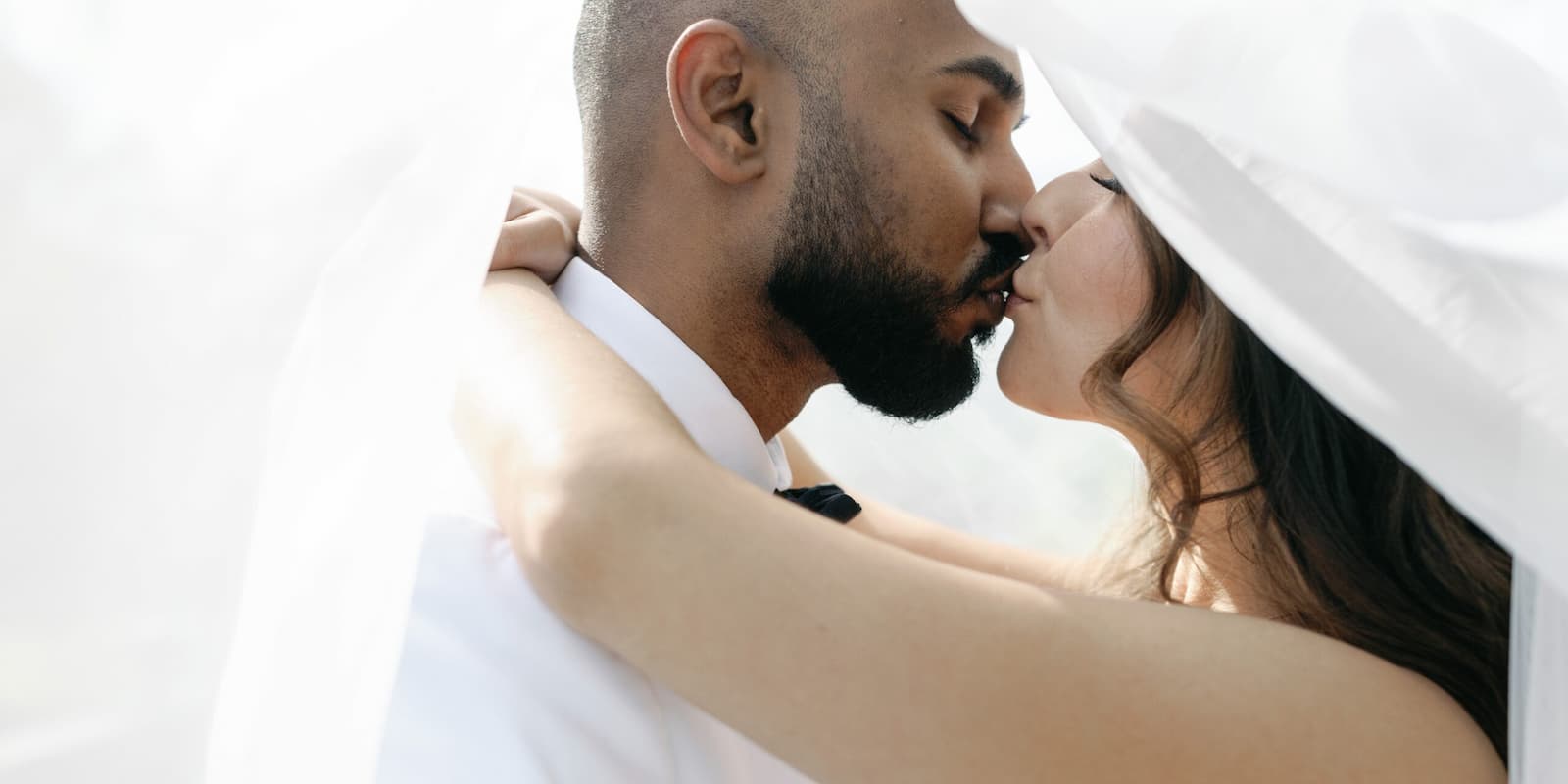 Bride and groom kissing under the bride’s veil during their wedding at the Pavilion at Haggin Oaks.