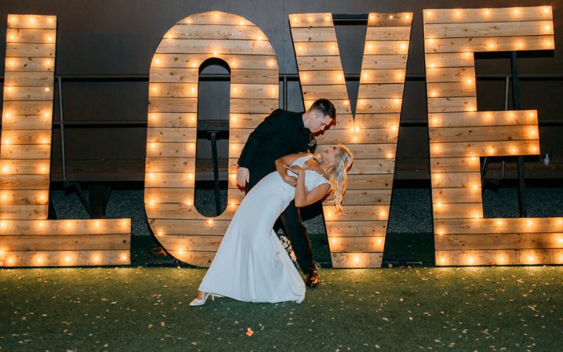 Bride and groom posing in front of illuminated LOVE letters during their wedding reception at The Pavilion at Haggin Oaks in Sacramento.